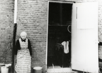 108723 Afbeelding van de wed. A. ('opoe') Weerenstein bij de achterdeur van haar huisje in de Mispelstraat 4 te Utrecht.